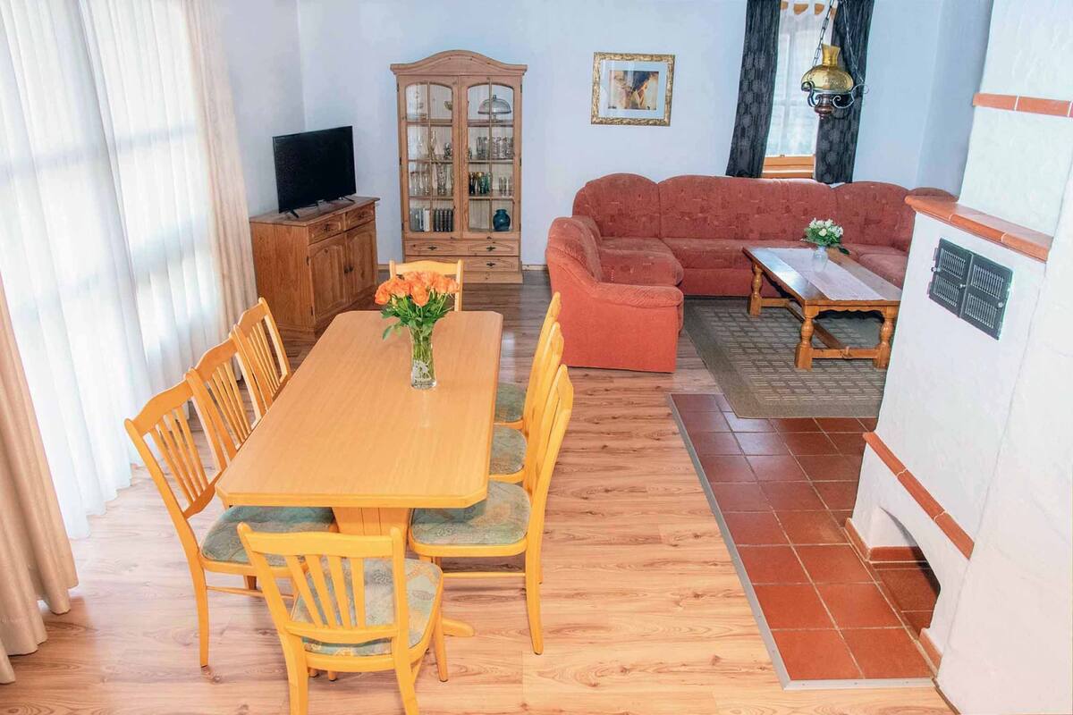 A living room with a wooden dining table, chairs, a sofa, and a cabinet.