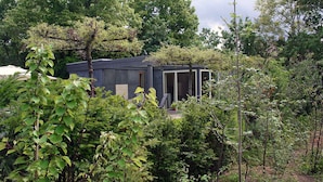 Un bâtiment moderne, de plain-pied, doté d’un toit plat et entouré d’une végétation luxuriante et d’arbres.