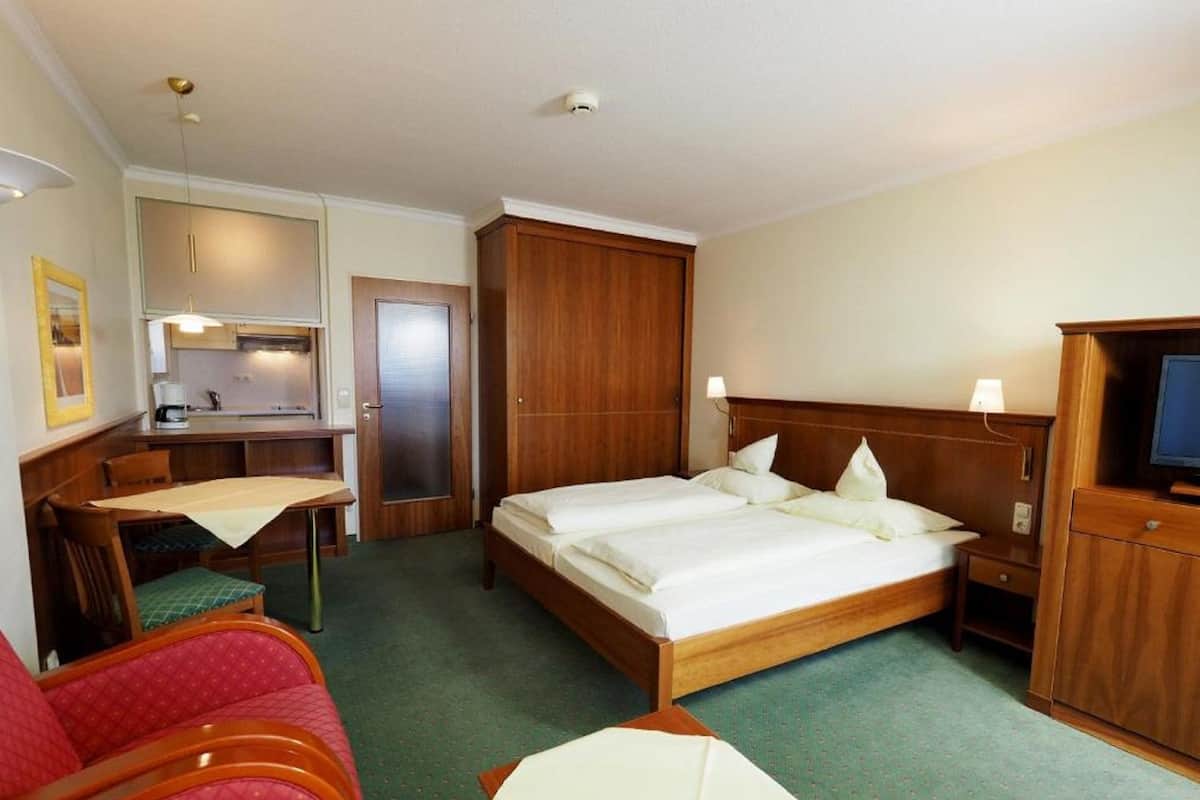 A hotel room with a bed, a desk, a chair, and a television.