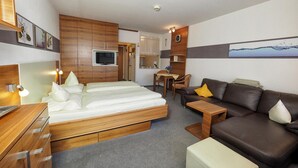 A modern bedroom with a wooden bed, a brown leather sofa, and a small dining table.