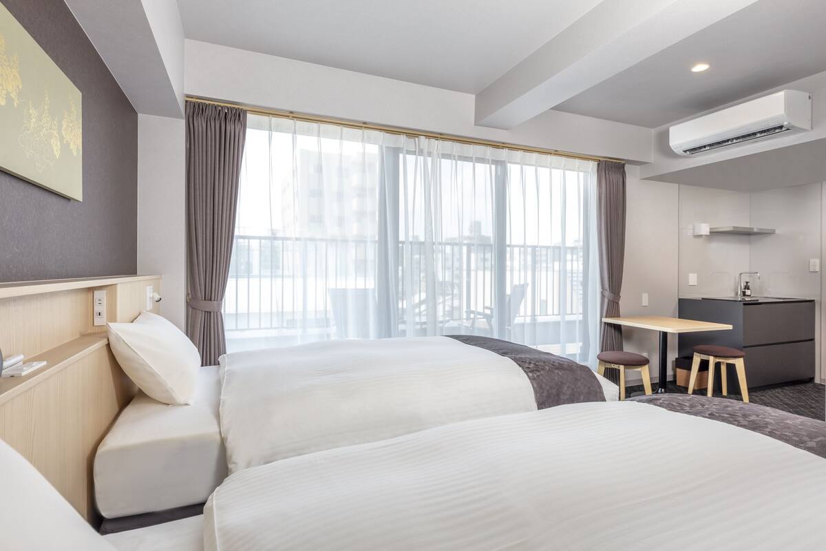 Une chambre d’hôtel avec deux lits, un bureau et une kitchenette.