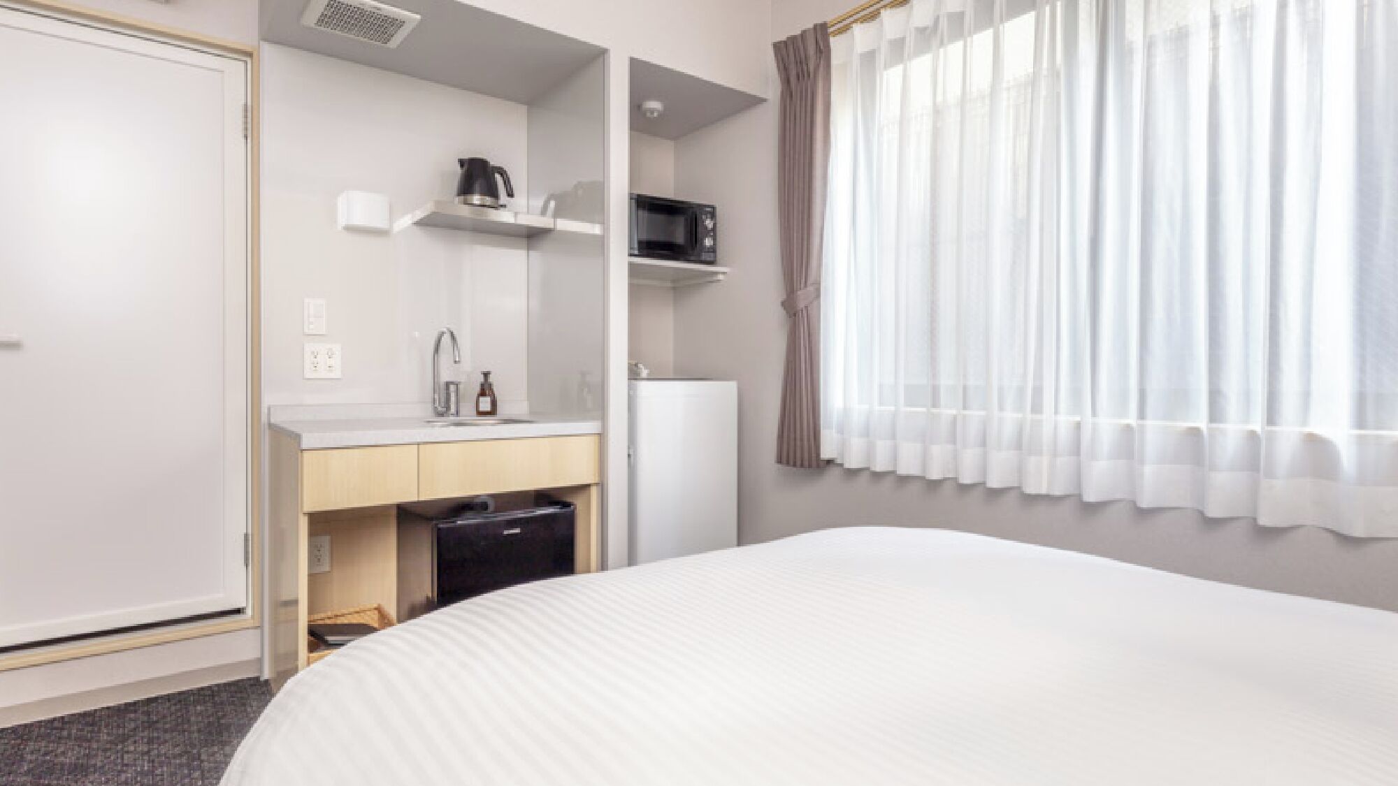 Une chambre d’hôtel équipée d’un lit, d’un lavabo, d’un four à micro-ondes et d’un réfrigérateur.