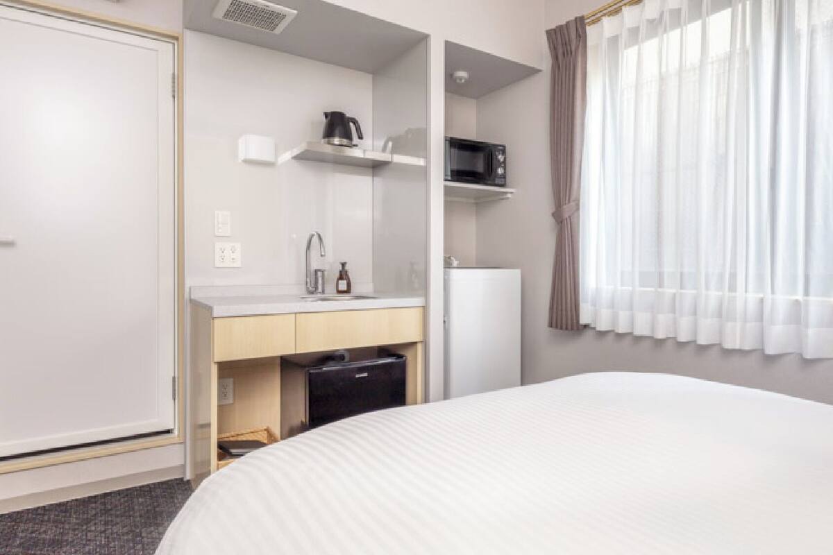 Une chambre d’hôtel équipée d’un lit, d’un lavabo, d’un four à micro-ondes et d’un réfrigérateur.