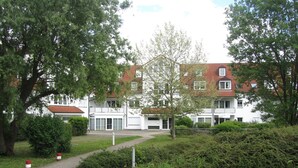 A building with a red-tiled roof, white walls, and multiple windows. There is a paved pathway leading to the entrance. - Ferienwohnungen an der Therme (Bad Rodach)