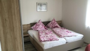 Ein Doppelbett mit hölzernem Kopfteil, zwei Zierkissen und ein kleines gerahmtes Bild an der Wand.