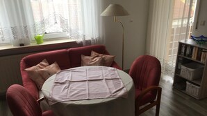 Ein gemütliches Zimmer mit einem roten Sofa, einem runden Tisch und einer Stehlampe.