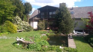 A house with a garden, a pond, and a deck with outdoor furniture. - Ferienhaus Sine Tempo (Marktleugast)