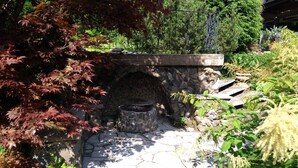A stone archway leading to a stone bench with a fire pit underneath. - Ferienhaus Sine Tempo (Marktleugast)