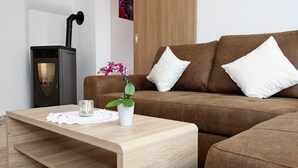 En moderne stue med en brun sofa, hvide puder, et træbord, en lille potteplante og en sort pejs.