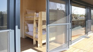 A wooden bunk bed room with a sliding glass door leading to an outdoor area. - Steigerwald-Apartments (Ebrach)