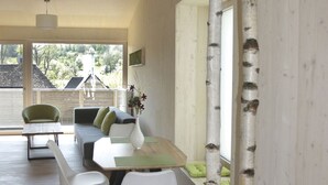 A modern interior with a dining area, wooden floors, and birch tree accents. - Steigerwald-Apartments (Ebrach)