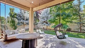 An outdoor patio with a round table, swing chairs, and a sofa. - Entertainment Castle With Theatre Room! (Meridian)