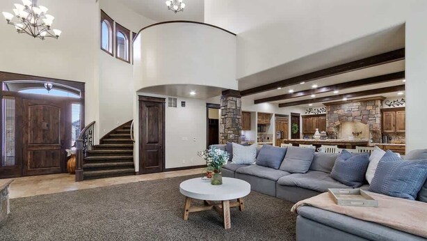 A spacious living area with a staircase, a stone fireplace, and a large gray sectional sofa. - Entertainment Castle With Theatre Room! (Meridian)
