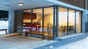 A modern building with a glass entrance, wooden benches, and a visible kitchen area.
