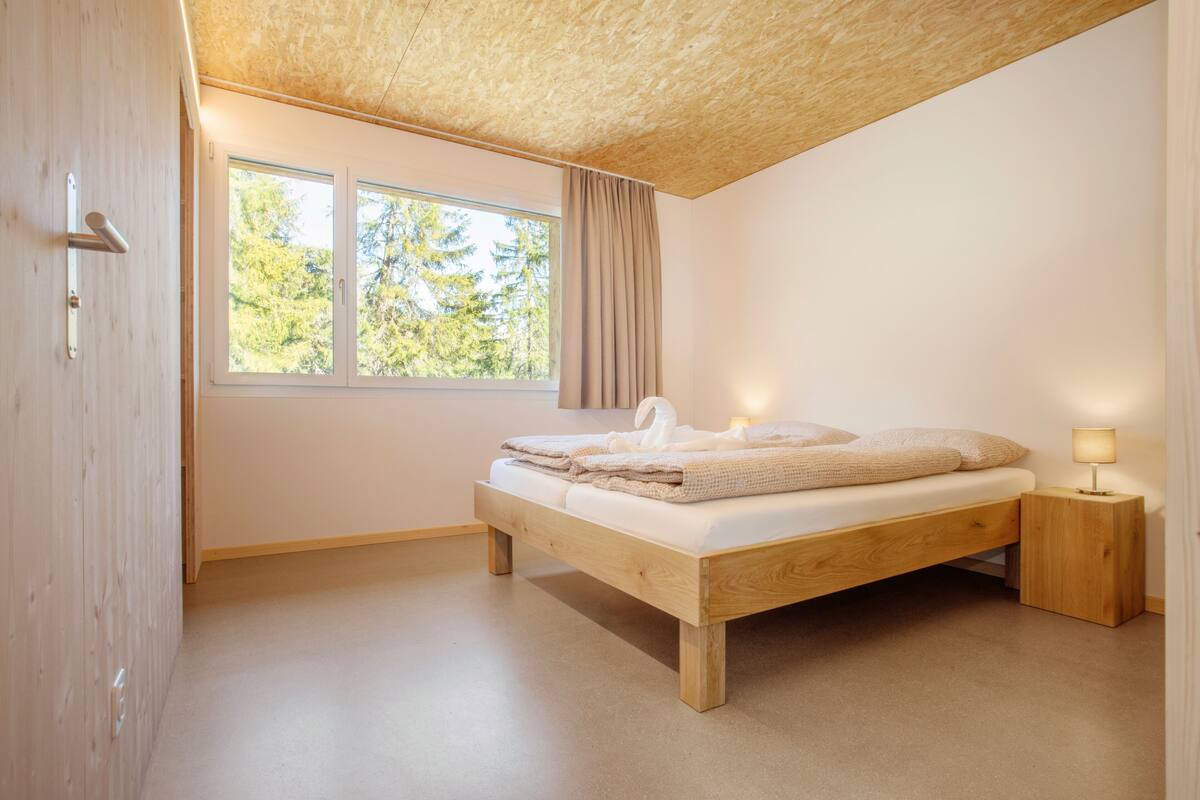 Una camera da letto con un letto di legno, una finestra con tende e una lampada da comodino.