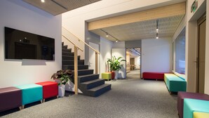 A modern interior with a staircase, colorful seating areas, and a large window.