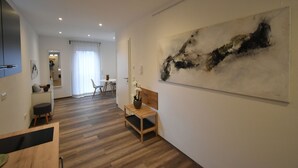 Uma sala de estar moderna com um banco de madeira, uma grande pintura abstrata e uma área de refeições ao fundo.