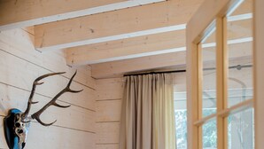 A bedroom with a bed, pillows, a wooden ceiling, and a deer skull mounted on the wall. - Chalet Bischofsmühle (Helmbrechts)