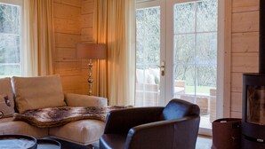 A cozy living room with a sofa, armchair, and a fireplace. - Chalet Bischofsmühle (Helmbrechts)