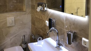 Un baño moderno con un lavabo blanco, inodoro y espejo.