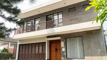 Uma casa moderna de dois andares com varanda, portas de madeira grandes e garagem.