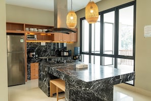 A modern kitchen with a marble island, stainless steel appliances, wooden cabinets, and large windows. - Kamala Plantation View 10BR Infinity pool+billiard (Cimenyan)