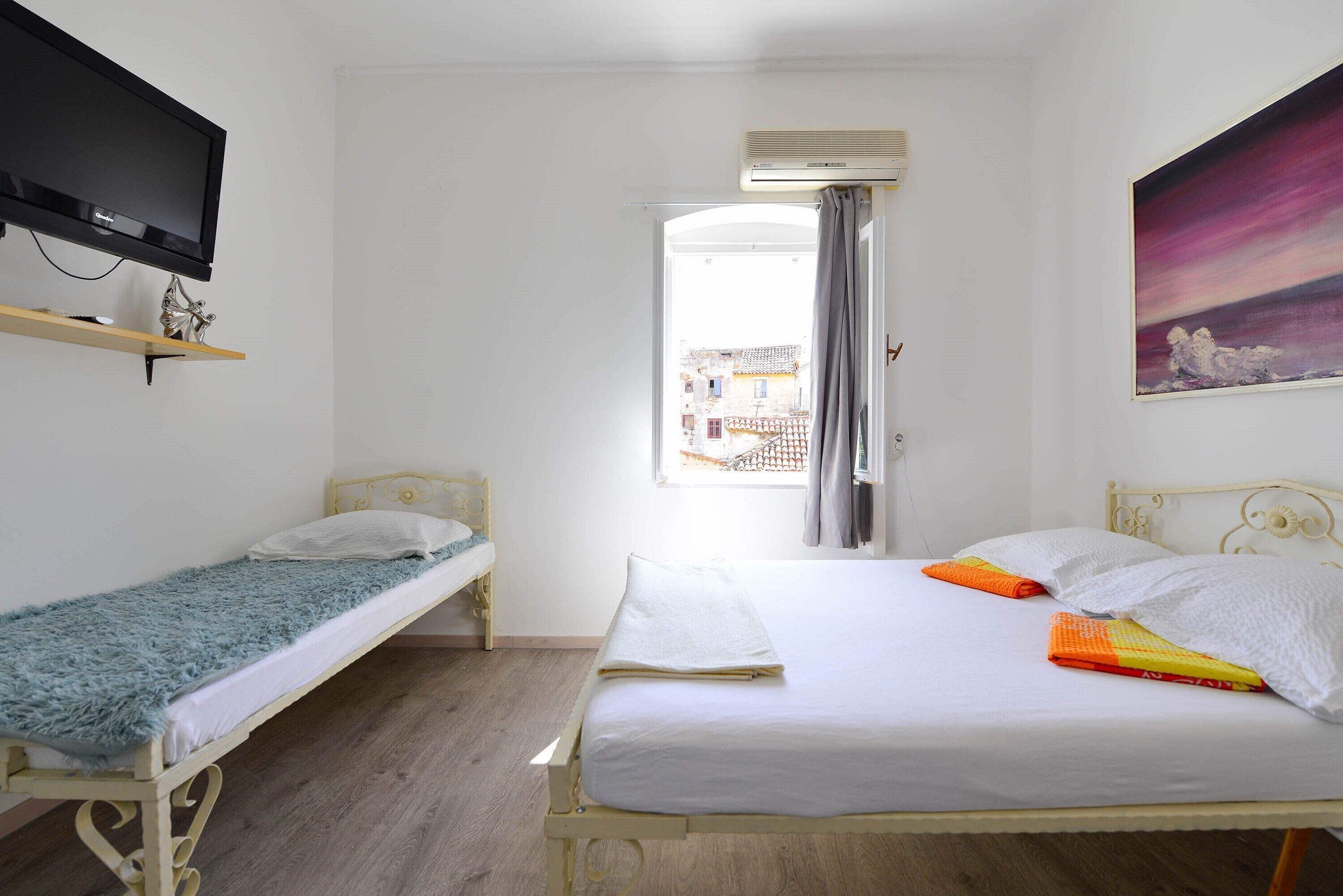 Una habitación con dos camas, televisión y un cuadro.