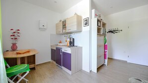 A compact kitchen with a dishwasher, a small dining table, and a chair. - Apartments Bulovic (Split)