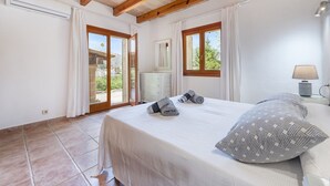 Un dormitorio con cama, mesita de noche, lámpara y vistas por la ventana.
