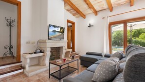 Una sala de estar con chimenea, un sofá, una mesa de centro y un televisor sobre la chimenea.
