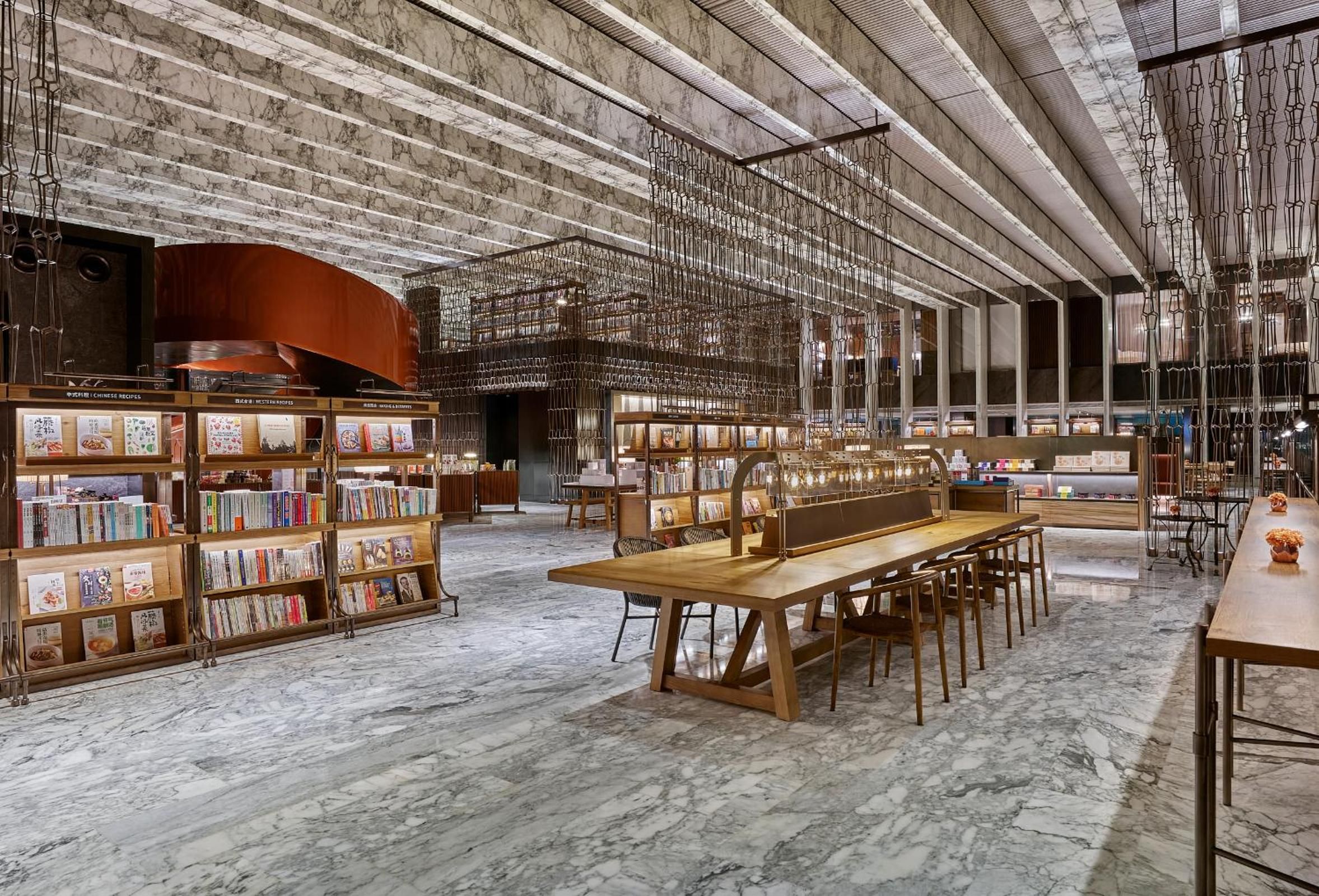 A spacious library with marble floors, wooden bookshelves, and a long wooden table.
