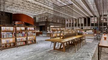 A spacious library with marble floors, wooden bookshelves, and a long wooden table.