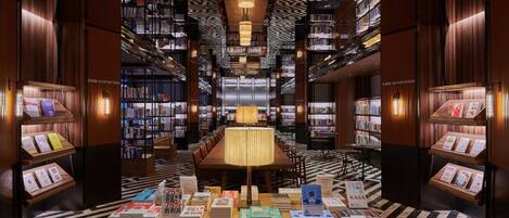 A library interior with bookshelves, a central table, and a patterned floor.