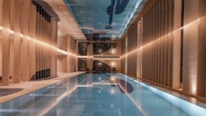A long, narrow indoor pool with a reflective floor, flanked by wooden paneling and recessed lighting. - Mumian Beijing Daxing International Airport, part of Hyatt (Daxing)