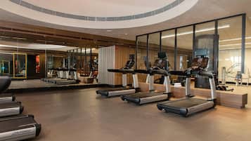 A modern gym with treadmills, exercise bikes, and mirrored walls.