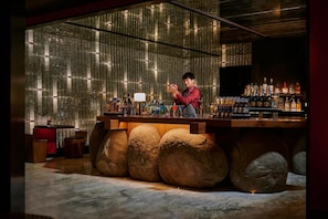 A bar with a bartender, a stone base, and a wall of bottles. - Mumian Beijing Daxing International Airport, part of Hyatt (Daxing)