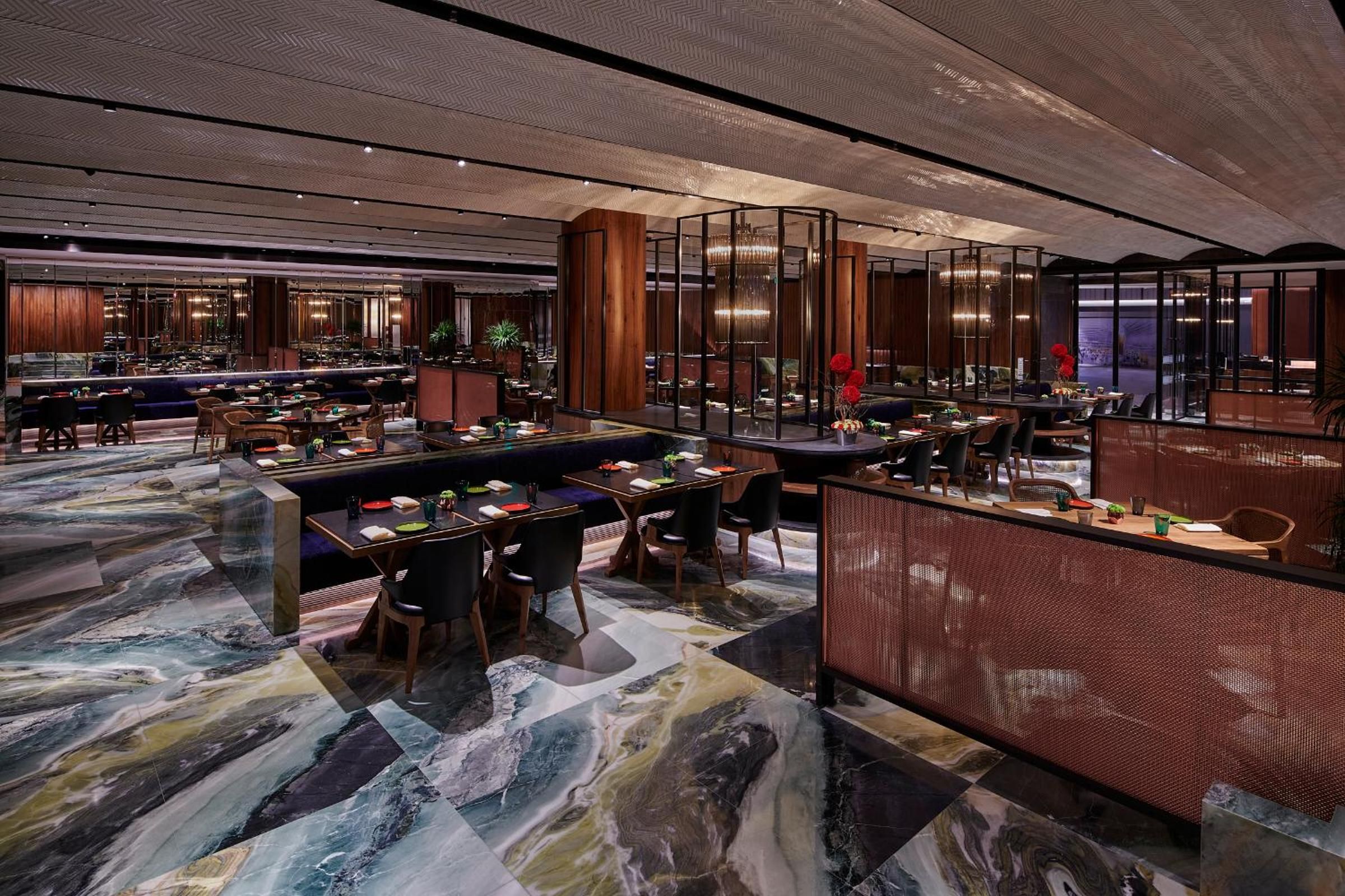 A modern hotel lobby with marble flooring, multiple seating areas, and a large bar.