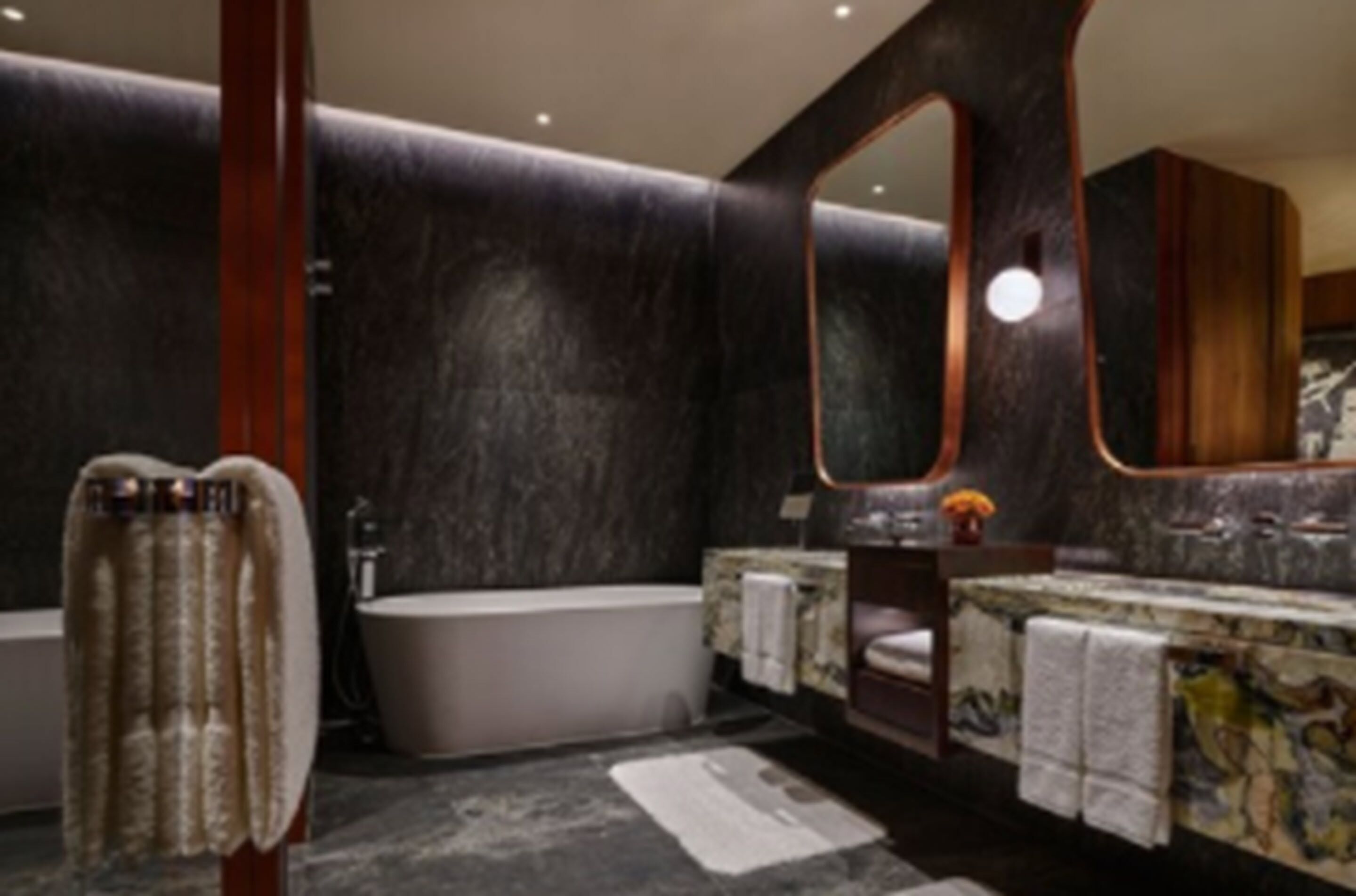 Un baño moderno con una bañera, un espejo grande y un tocador con encimera de mármol.