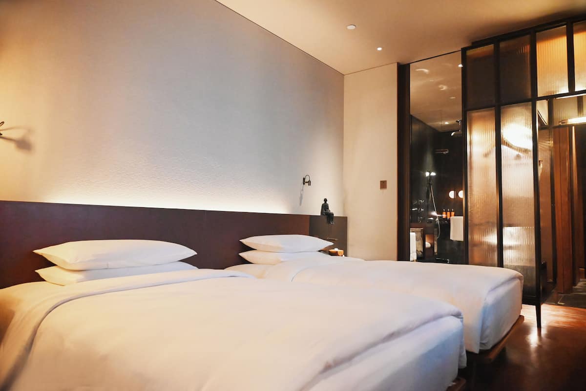 Ein Hotelzimmer mit zwei Betten, einem großen Spiegel und Blick ins Badezimmer.