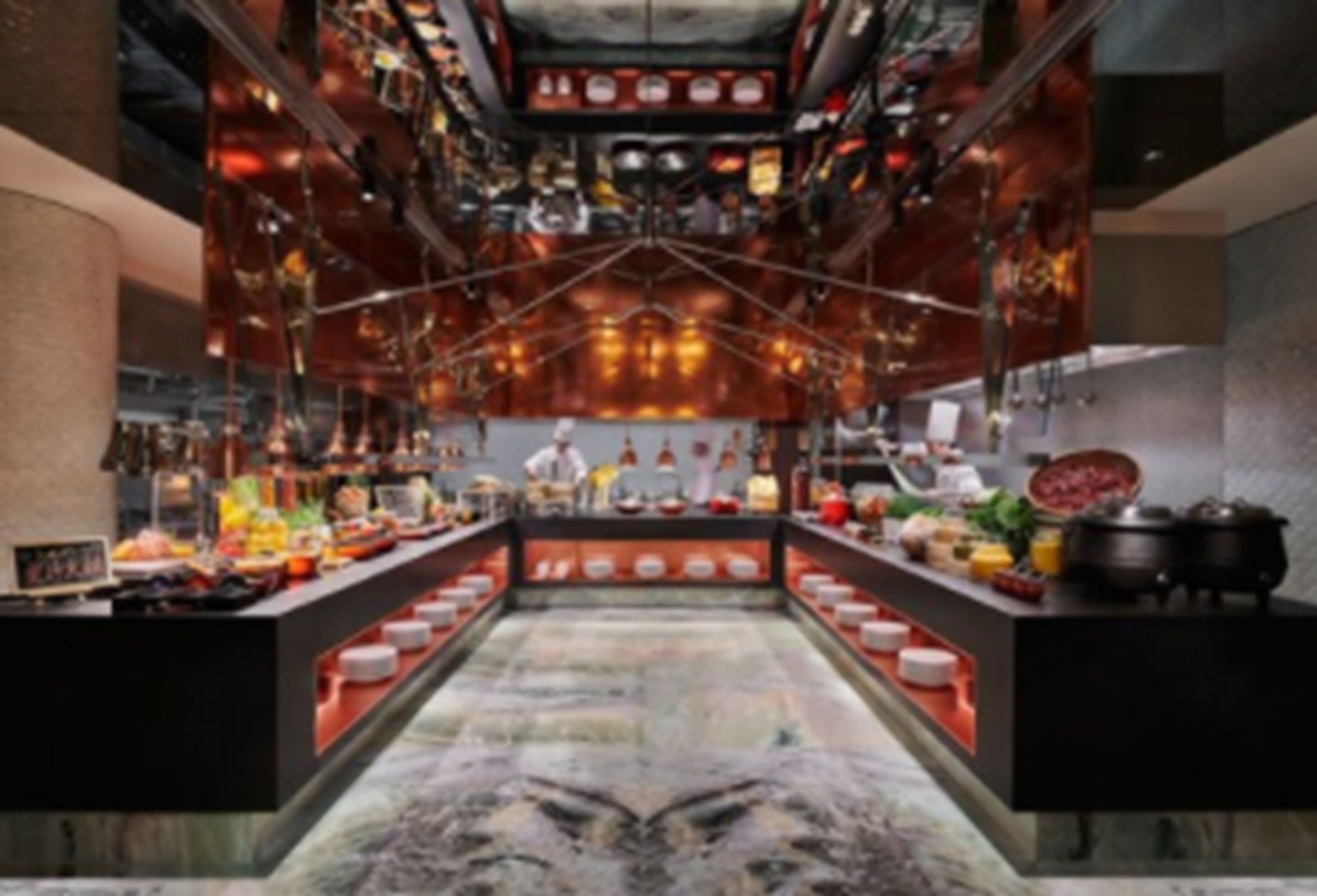 A modern kitchen with a central island, various cooking stations, and a high ceiling with exposed ductwork.