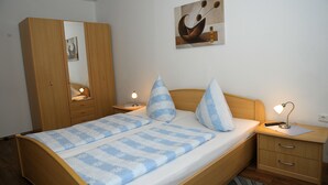 A bedroom with a bed, bedside tables, a wardrobe, and a painting on the wall. - Landgasthaus Zum Mönchshof (Wolframs-Eschenbach)