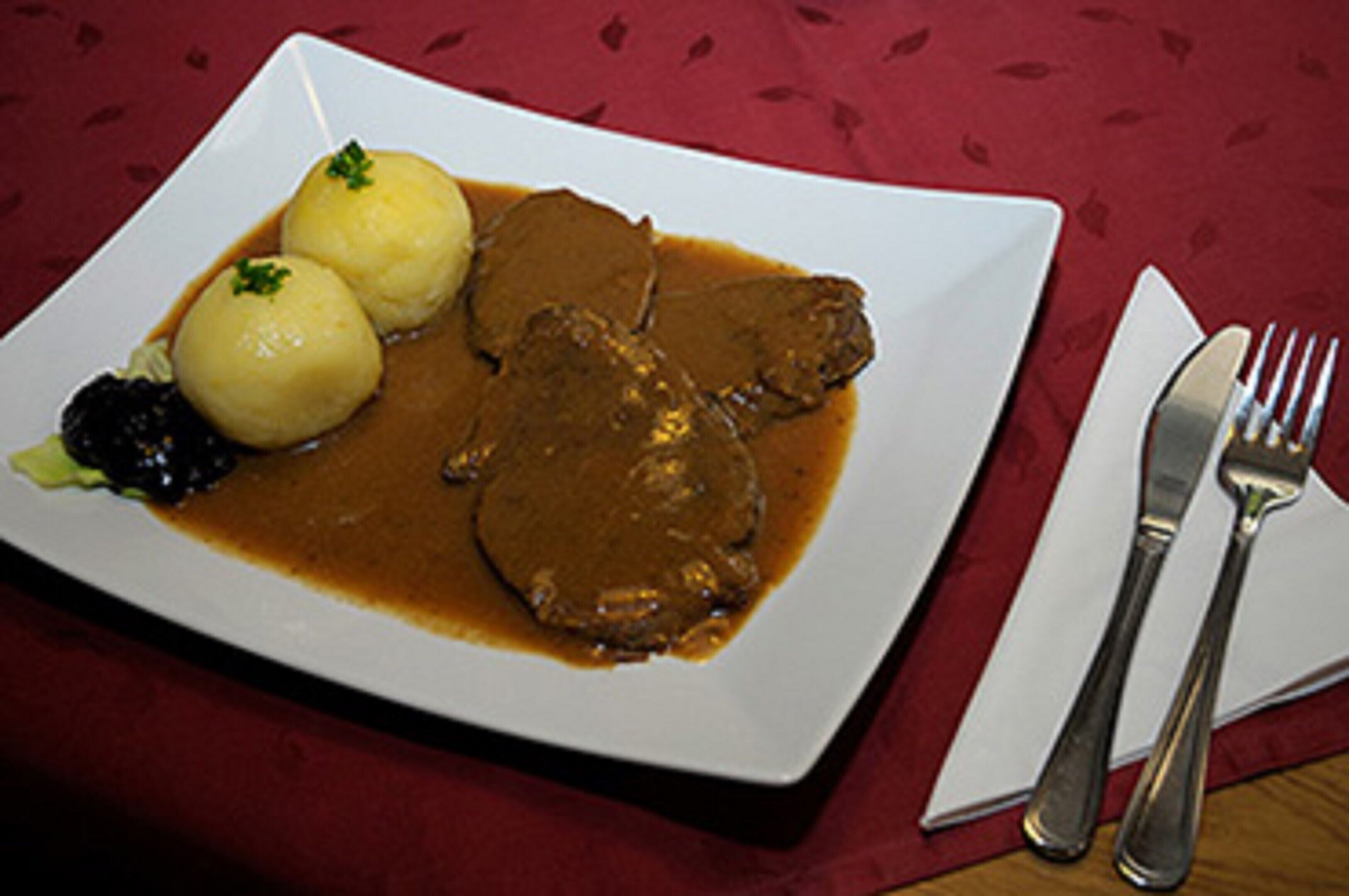 Un plato de comida con dos albóndigas y una porción de carne cubierta de salsa.