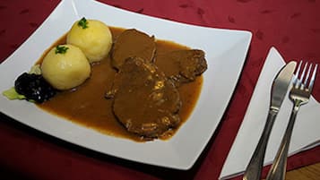 Un plato de comida con dos albóndigas y una porción de carne cubierta de salsa.