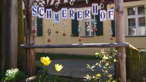 Un arco de madera con el letrero "SCHMERER OF" y elementos decorativos como adornos colgantes y faroles.