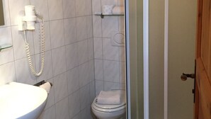 Un baño pequeño con inodoro, lavamanos y cabina de ducha.