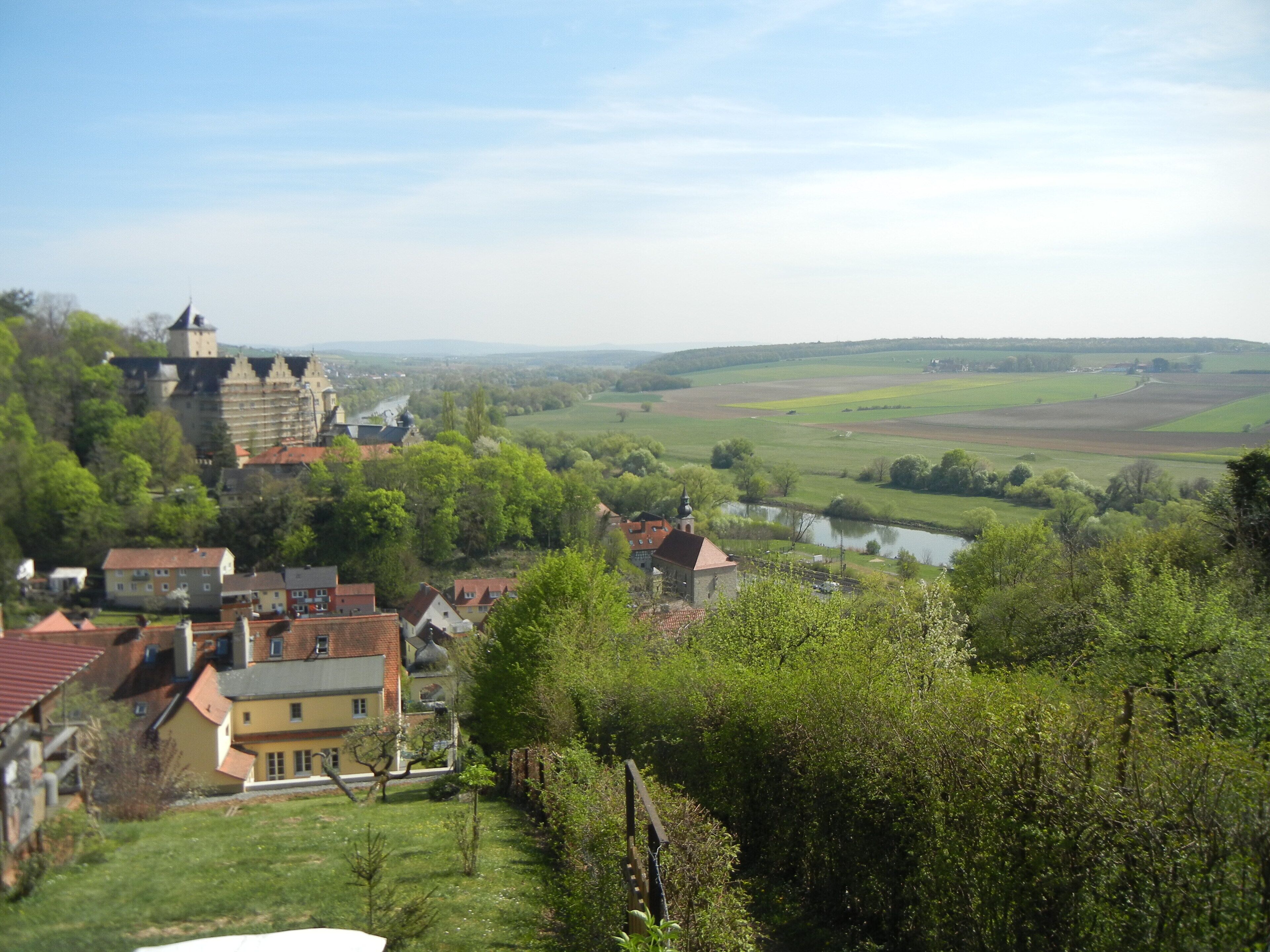 A historic town with a castle, houses, and a river.