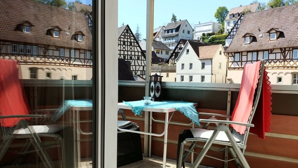 Un balcón con mesa, sillas y vistas a edificios tradicionales europeos.