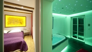 Un dormitorio moderno con cama, mesita de noche y un cuadro abstracto grande.