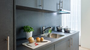 Una cocina moderna con armarios grises, un lavamanos de acero inoxidable y una planta en maceta.