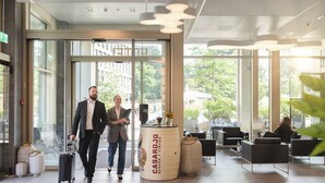 Un moderno vestíbulo de hotel con acceso de vidrio, mostrador de recepción y zonas de estar.